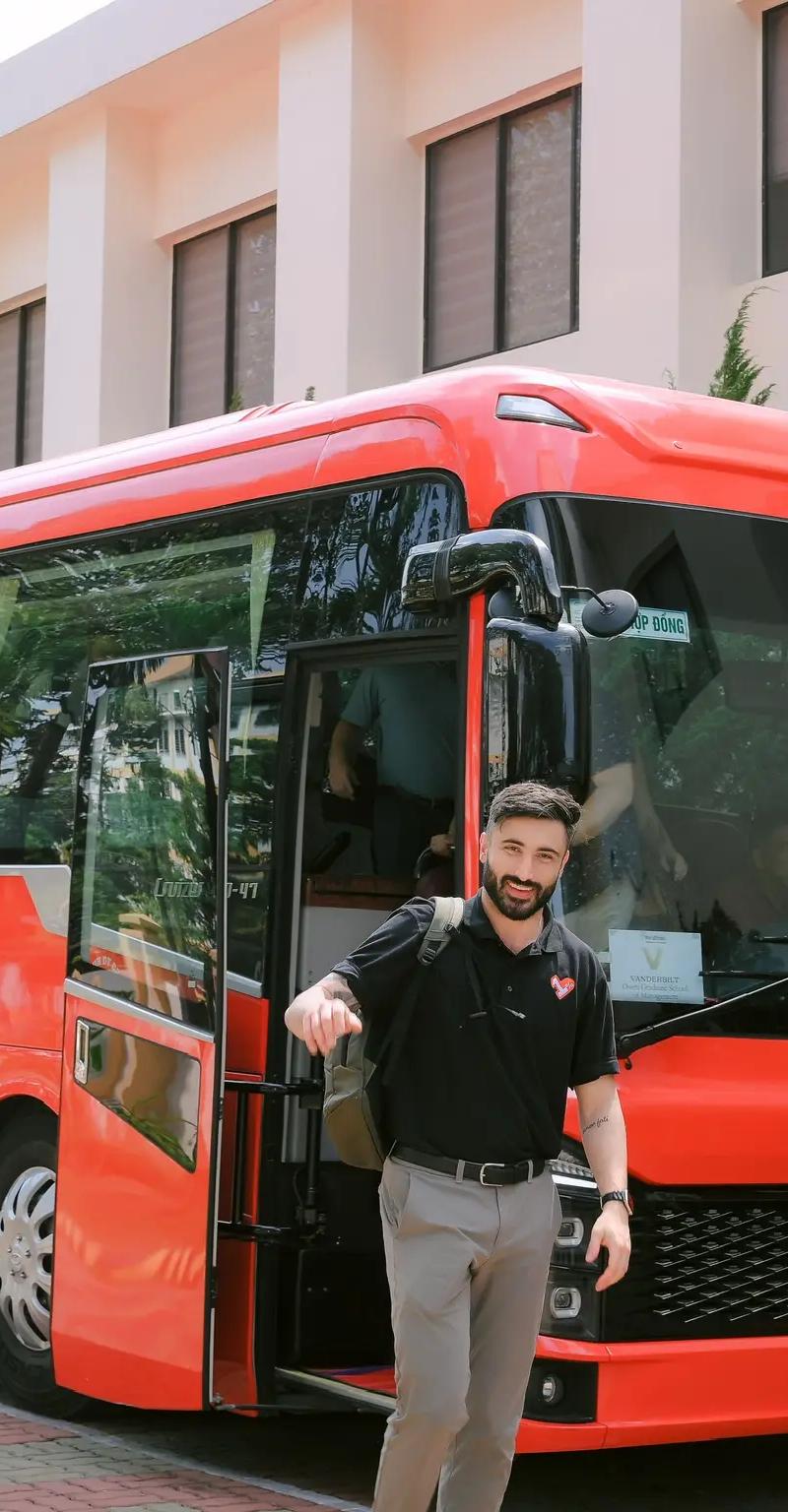 OPH embroidered polo in front of a red Vietnamese tour bus in Saigon
