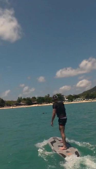 Wakeboarding off a Thai beach in the OPH trucker hat