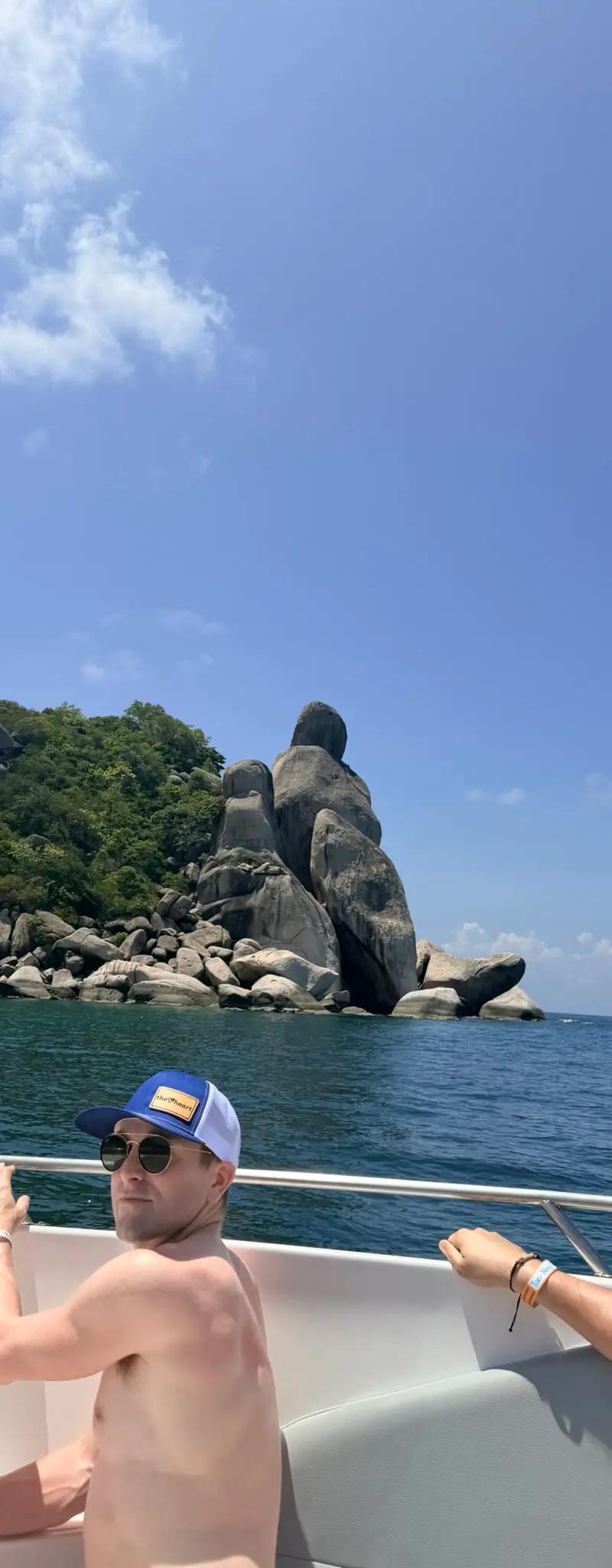 OPH leather-patch trucker hat on a boat with rocky Thai islands behind