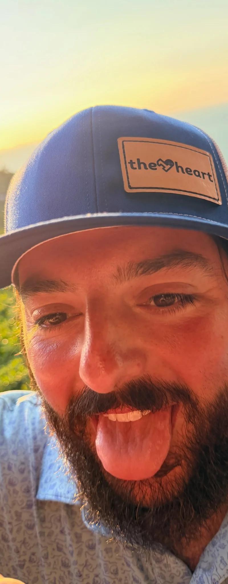 OPH leather-patch trucker hat at sunset with the Thai coast behind
